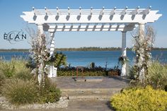 an outdoor wedding ceremony setup with flowers and greenery on the side by the water