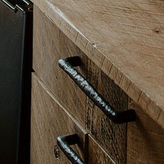 a wooden counter top with metal handles and knobs on the drawer, next to a black refrigerator