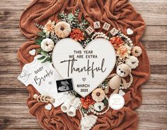 a heart shaped photo frame with flowers and other items on top of it that says, this year we are extra grateful