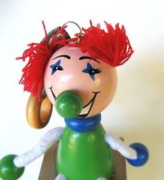 a green toy with red hair on top of a wooden table next to a white wall