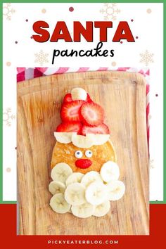 a santa pancake made out of bananas and strawberries on a wooden cutting board