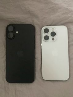 two iphones are laying next to each other on a bed with white and black covers