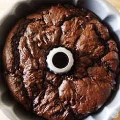 a chocolate cake in a pan with a hole in the middle and white frosting on top