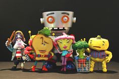 several toy figurines are posed in front of a robot