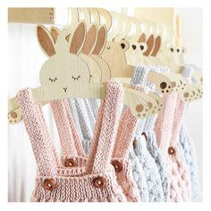 crocheted baby bibs hanging on a clothes rack with wooden pegs in the shape of animals