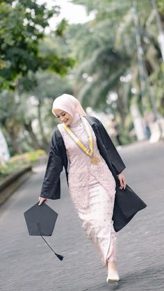 a woman in a hijab walking down the street with an umbrella on her head