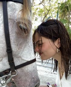 a woman petting the nose of a horse