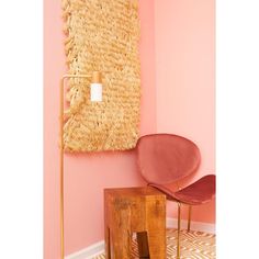 a chair and table in front of a pink wall with a large piece of grass hanging on the wall