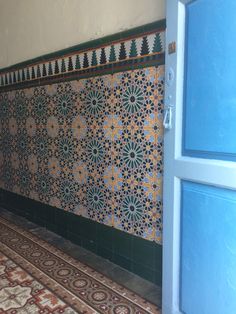 an ornate tile wall in a room with blue doors and green trim on the walls