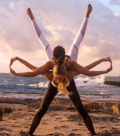 two women doing yoga on the beach with their arms in the air and hands behind them