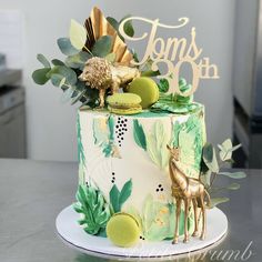 a green and white cake with gold decorations on it's top is sitting on a table