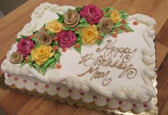 a large white cake with flowers on it sitting on a wooden table next to a knife