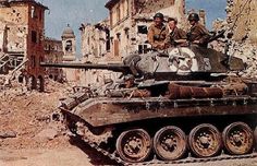 two men sitting on top of a tank in the middle of an old city street