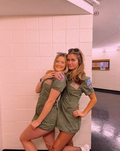 two women in army uniforms posing for the camera with their arms around each other, both wearing fishnet stockings