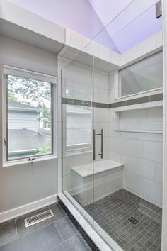 a walk in shower sitting next to a window on top of a tiled flooring