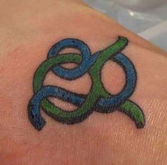 a tattoo on the arm of a woman with an omen symbol in blue and green