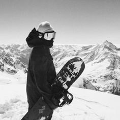 a snowboarder is standing on the top of a mountain with his board in hand