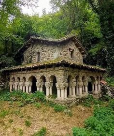 an old stone building sitting in the middle of a forest filled with lush green trees