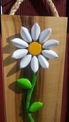 a wooden sign with a white flower on it's side hanging from a rope