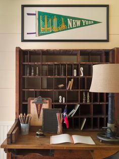 an old wooden desk with books and other items on it in front of a framed new york sign