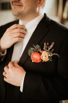 a man wearing a suit and tie with flowers on his lapel