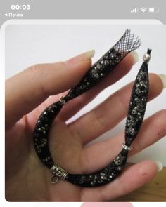 a woman's hand holding a black beaded bracelet with an arrow on it