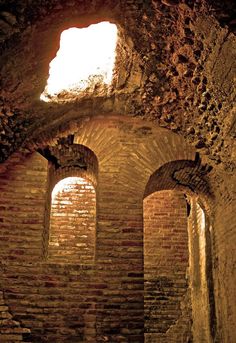 the light shines through two windows in an old brick building with arches and bricks