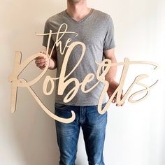 a man holding up a wooden sign that says the roberts