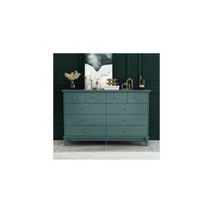 a green dresser with gold handles and knobs on the top, against a dark green wall