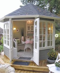 a gazebo sitting on top of a wooden deck next to a table and chairs