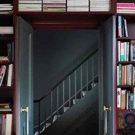 an open door leading to a bookshelf filled with lots of books next to a stair case