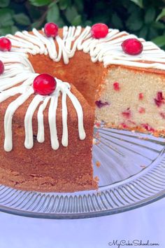 a cake with white frosting and cherries on top sitting on a glass plate