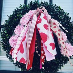 a valentine's day wreath with pink roses and hearts on it hanging from the front door