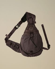 a gray bag hanging from the side of a white wall with straps attached to it