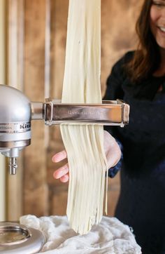 a woman is making pasta with a machine