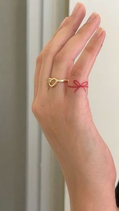 a woman's hand wearing a gold ring with a red ribbon tied around it