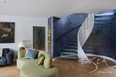 a living room filled with furniture next to a spiral stair case and painting on the wall