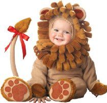 a small child in a lion costume sitting on the ground with a red ribbon around it's neck