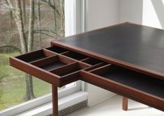 a wooden desk with drawers in front of a window