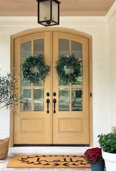 the front door is decorated with wreaths and potted plants