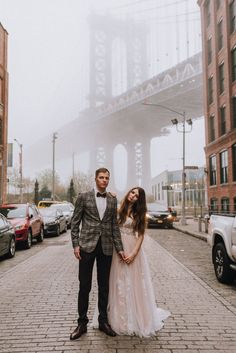 a man and woman standing in front of a bridge on a cobblestone street