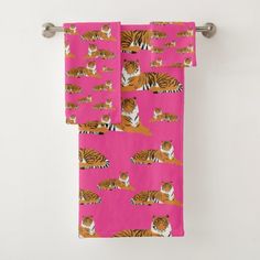 a pink towel with tiger print on it hanging from a metal bar in front of a white wall