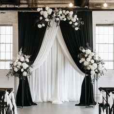 a black and white wedding ceremony setup with flowers on the back drop cloth drapes