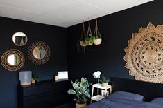 a bedroom with black walls and plants hanging on the wall above the bed, along with other decorations