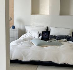 an open laptop computer sitting on top of a bed in a room with white walls