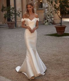 a woman in a white dress posing for the camera with her hand on her hip