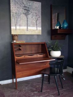 a piano sitting in front of a painting on the wall next to a chair and table