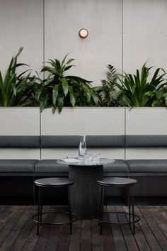 two tables and chairs with plants on the wall behind them in front of a bench