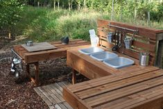 an outdoor kitchen made out of wooden pallets with sink and counter tops on the side