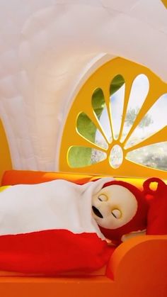 a doll is sleeping on an orange bed